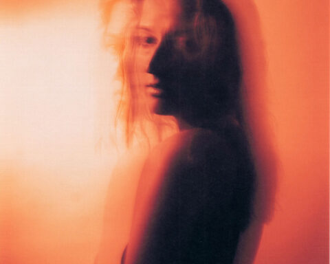 An amber filtered, blurred photo shot of Jenny Kern posing over her shoulder, in promotion of her single "Move On".