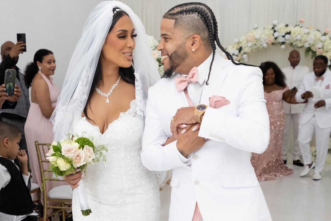 Photo of International Nova and Cristina Ferreira on their wedding day as they walk down the aisle with their arms interlocked. They are looking at each other with pure desire and attractiveness flowing between them.