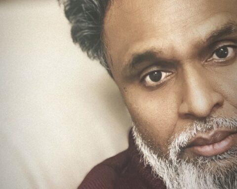 Promotional photo for "For Better or For Worse" featuring YBTB which sees a headshot of Chin Injeti, but only half his face in a selfie. He is wearing a burgundy jumper that makes his white beard look brighter.