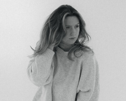 Promotional photo for "No Rest" which is a black-and-white mid-shot of Lisa Curtis wearing a jumper with her right hand tousling her blonde-brown hair.