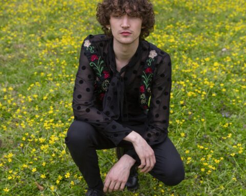 Promotional photo for "Star Crossed Lovers" which sees Otto Aday crouching in a field of grass.