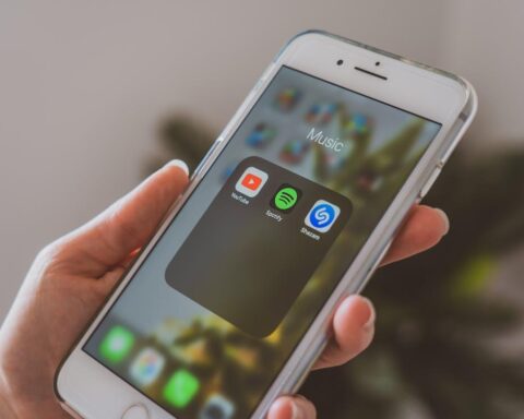 Free Person Holding an iPhone Opened on a Music Folder  Stock Photo