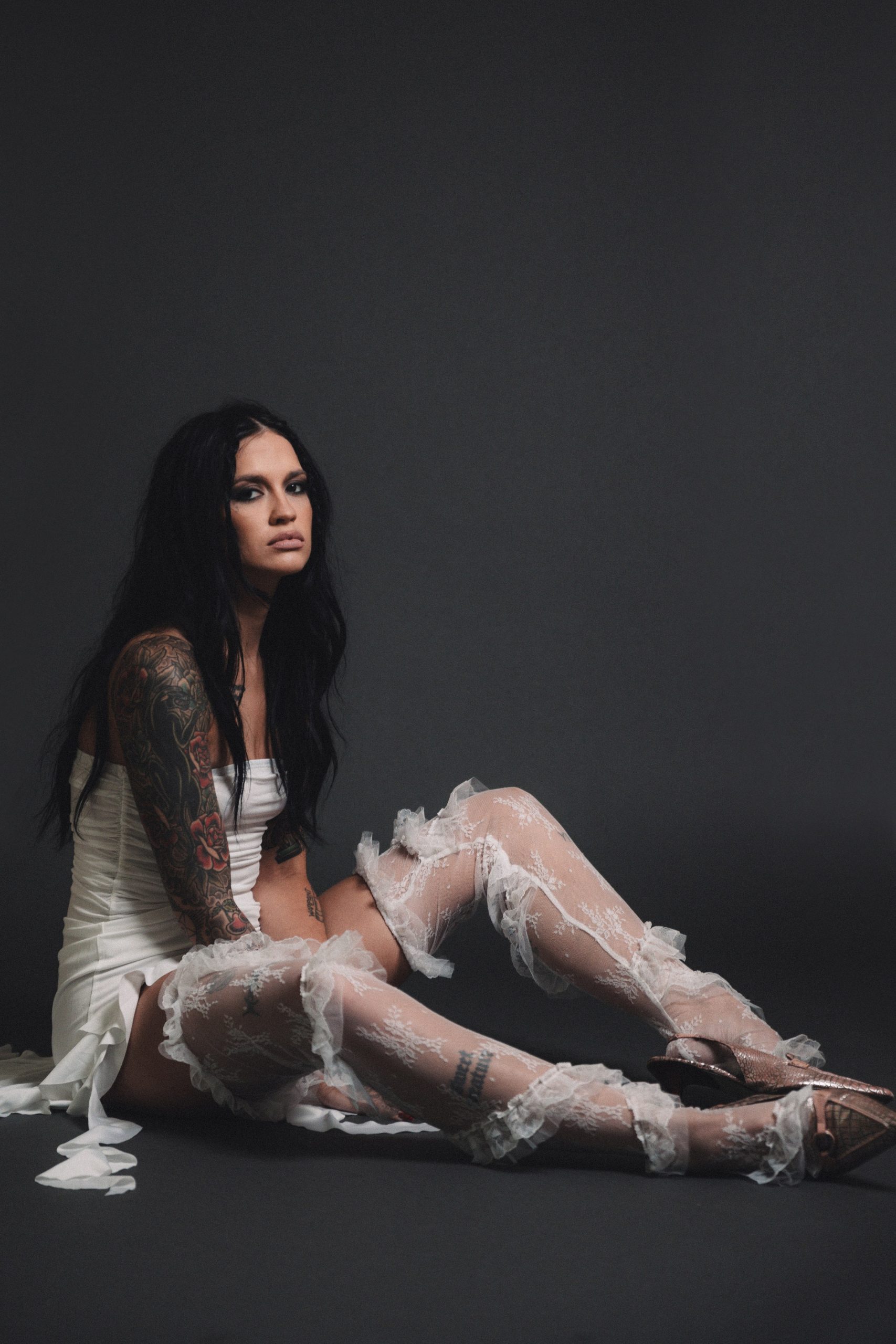 Promotional photo for "Unforgivable" which sees TAELA sitting on the floor wearing a white netted dress.